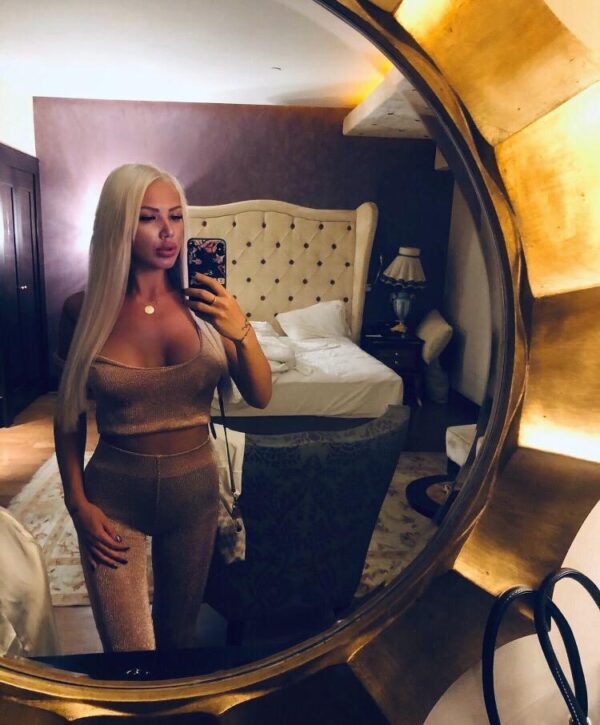 Paddington Escort Moinca Sexy Blonde Busty escort in London. Selfie wearing gold tight legging & matching bra top at 24hr London Escorts